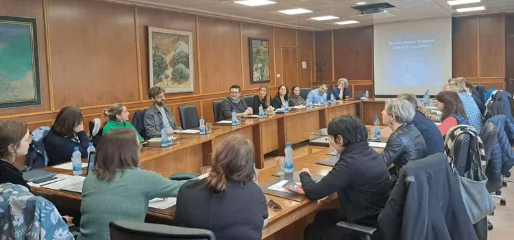 Participants around a conference table during the PartnerUp study visit in Cyprus, a slide on Cyprus's HRDA projected.