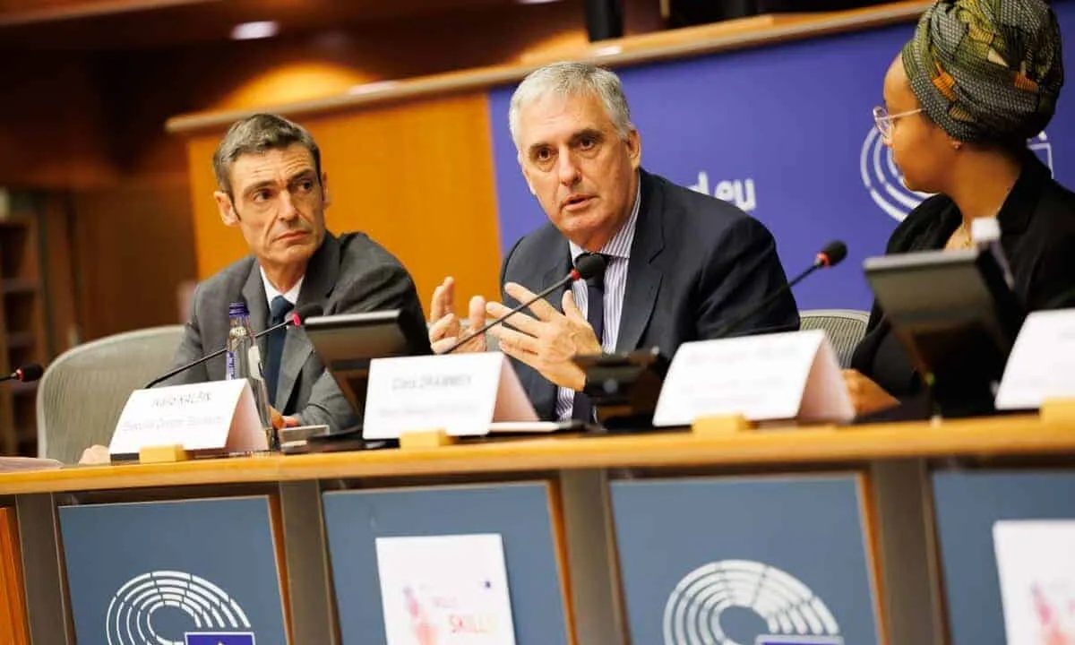 Three individuals at a panel discussion, European Parliament setting.